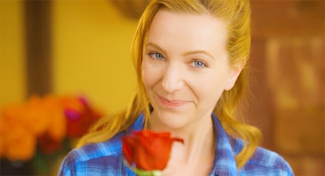 Smiling woman in German market, extending red rose.