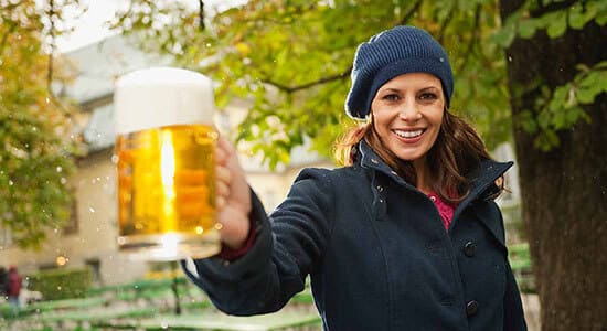 Smiling woman holding out a mug of beer.