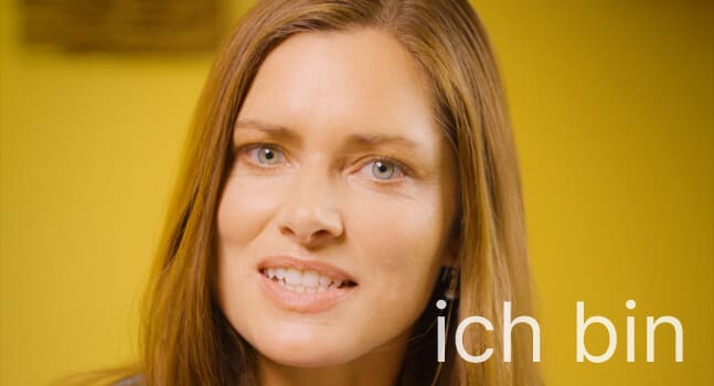 German teacher smiling kindly next to words "ich bin", meaning "I am" in German.