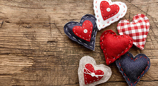 Small hand-made heart cushions on a wooden table.