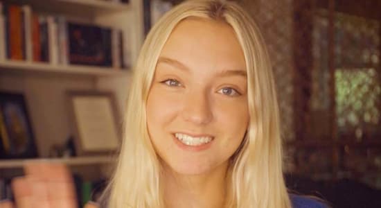 Female German tutor waving with welcoming smile.