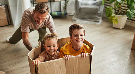 Father playing with two sons by pushing them in a box. The word for sons in German has a long O umlaut before the letter H.