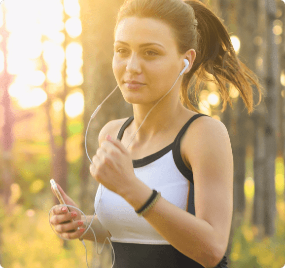 Woman jogging in the woods with headphones.